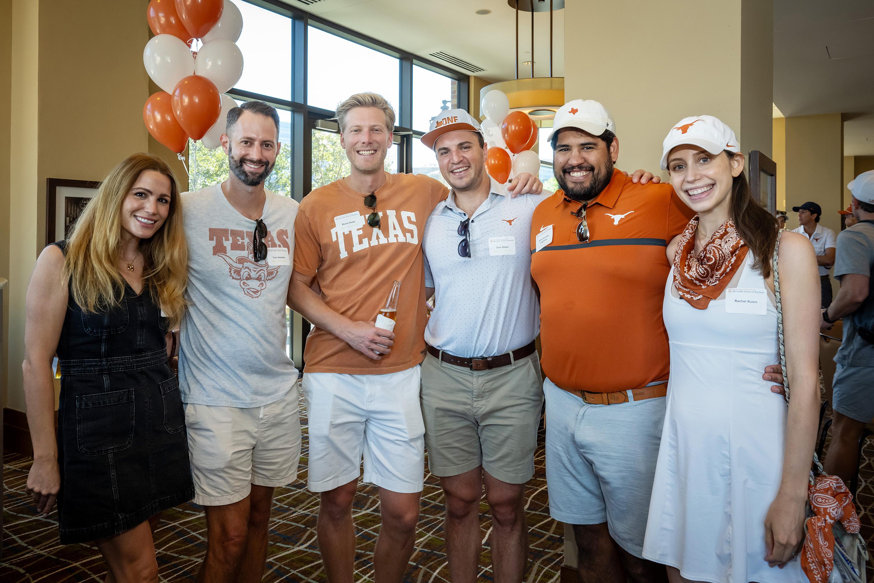 Group of 6 posed at indoor tailgate.