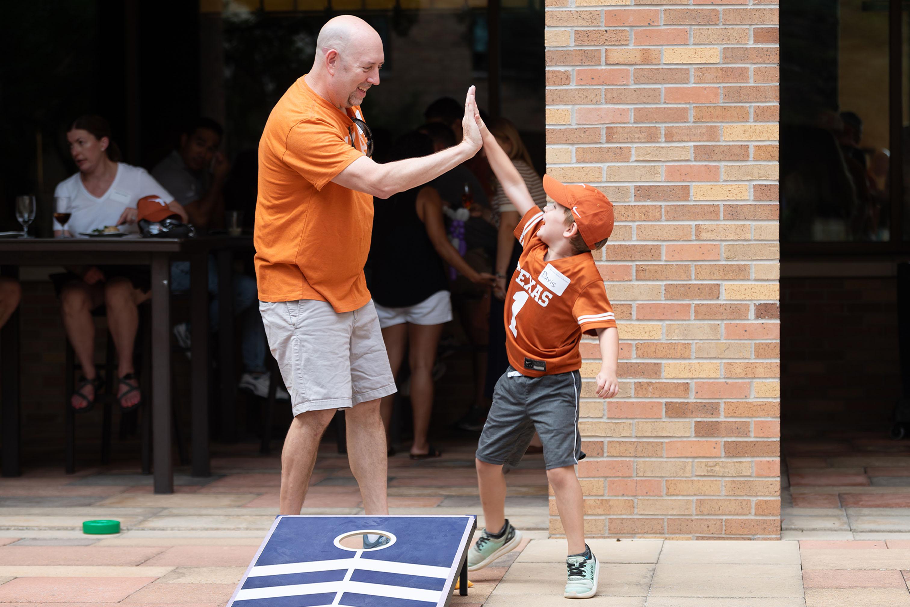 (Assumed) father and son high fiving at Tailgate event.