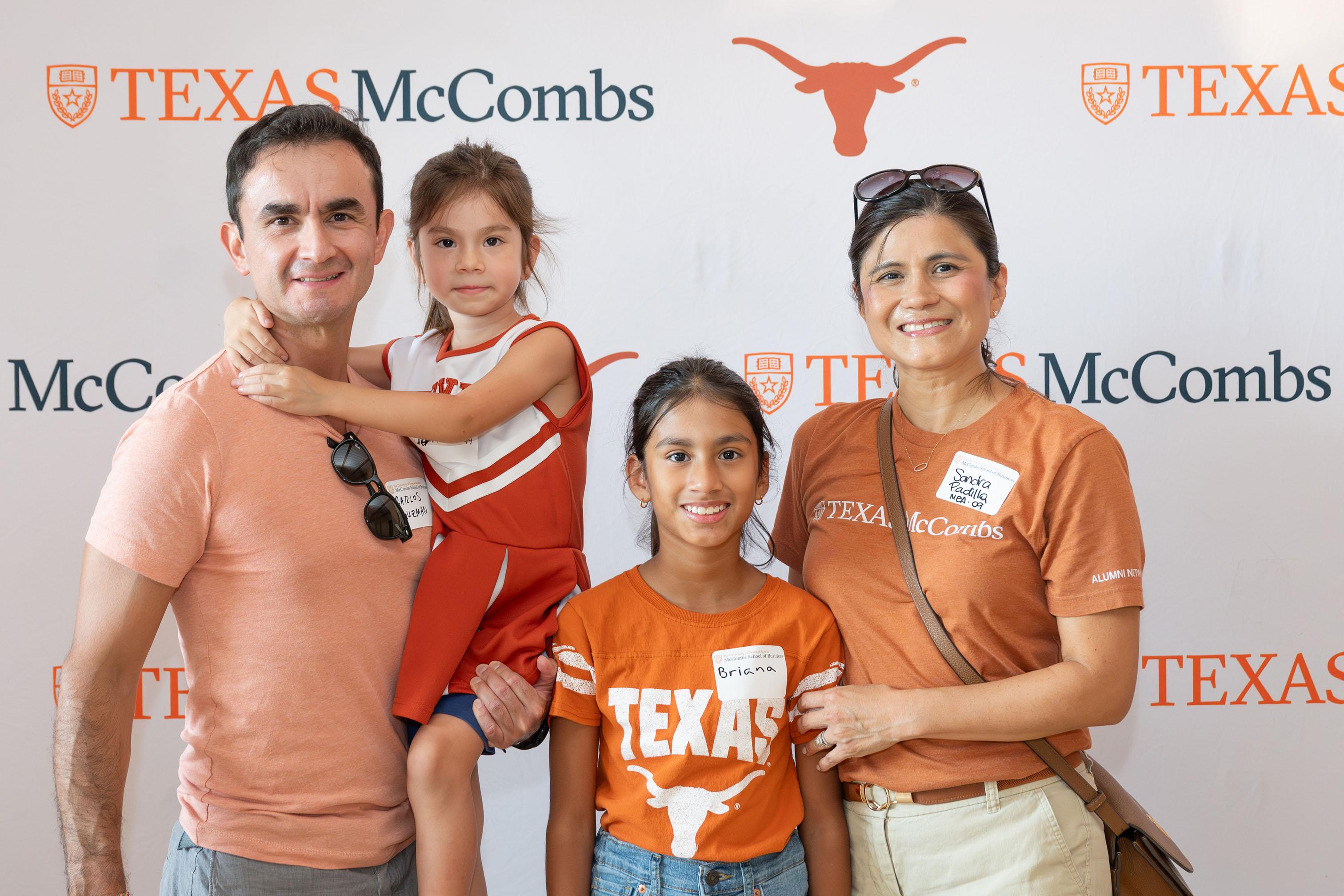 Family of four posed in front of photo opportunity background.